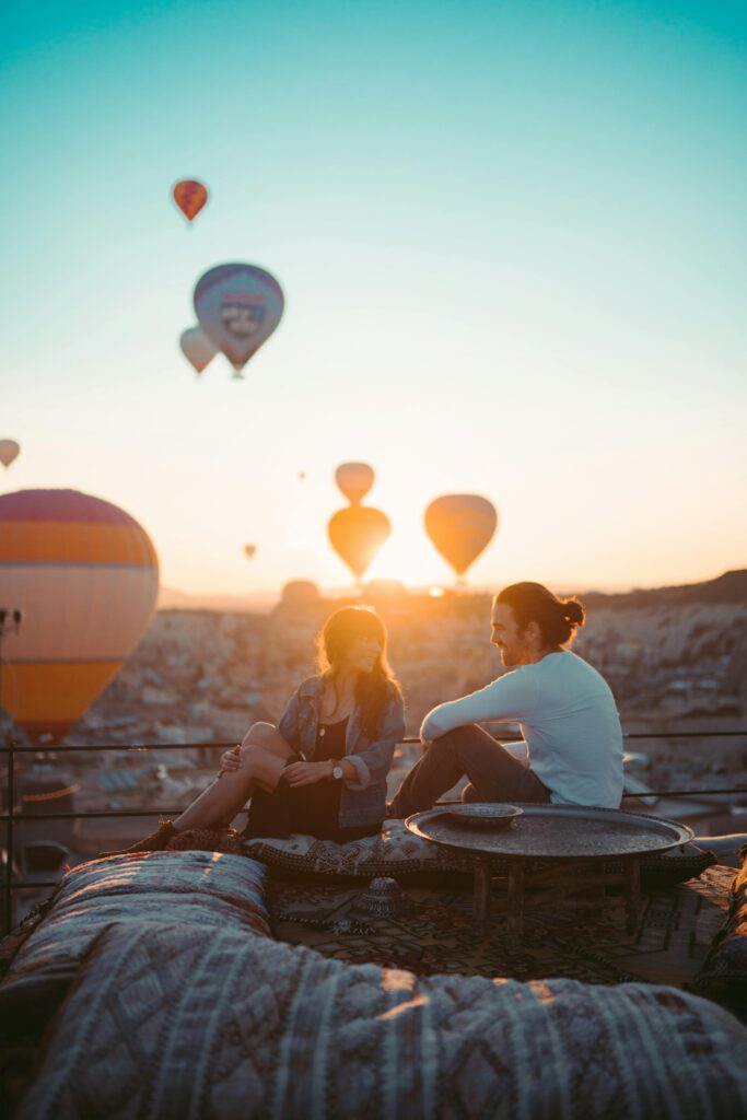 A couple enjoys a romantic sunrise with hot air balloons in Cappadocia, Turkey.